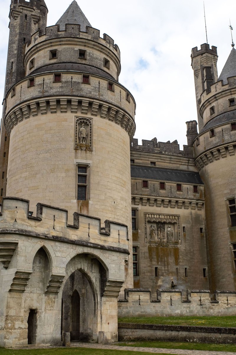 The Château de Pierrefonds rising above the village — soaring round towers, machicolated ramparts and steep conical roofs catching the light against the Forest of Compiègne. Pierrefonds, Oise, France.